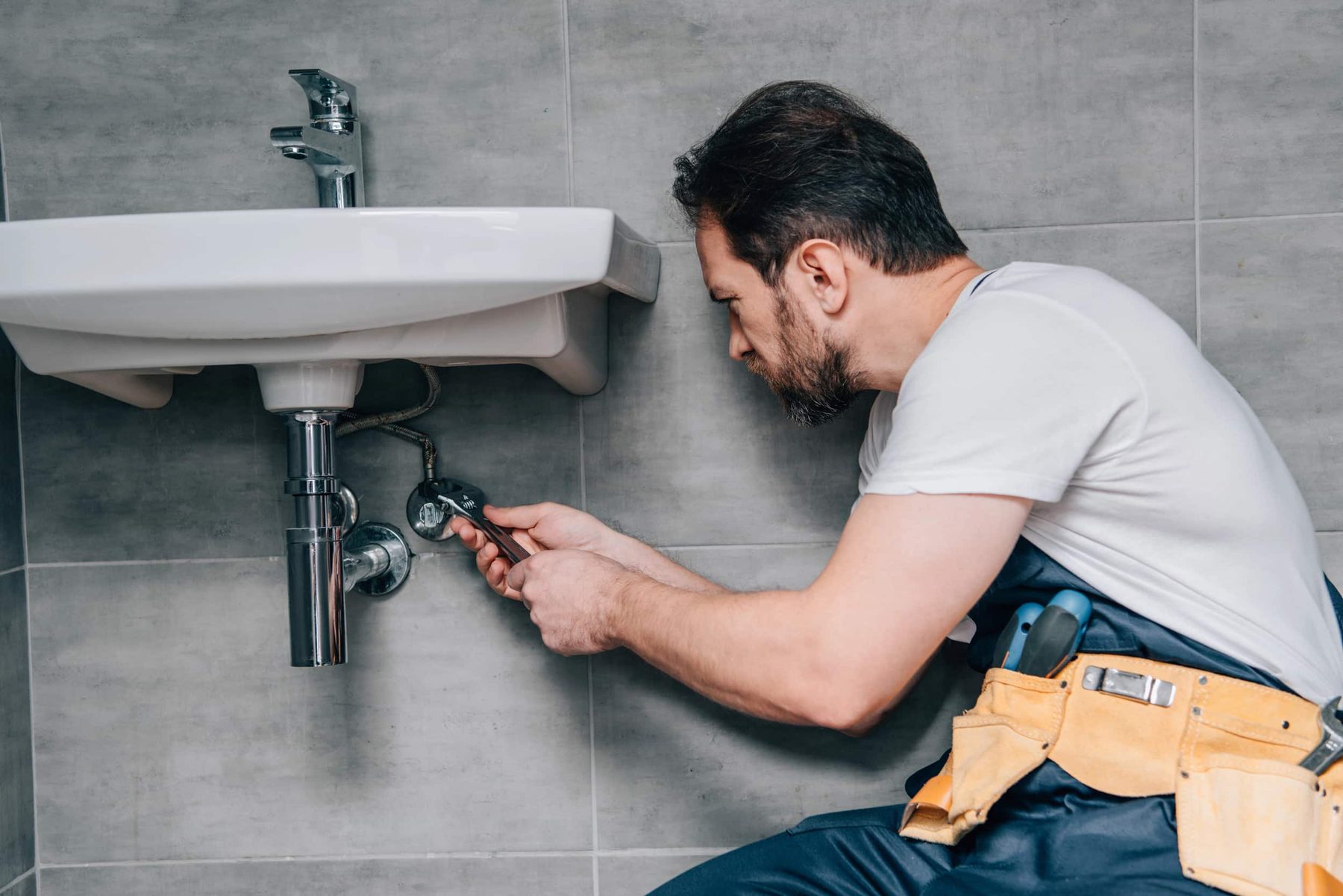 Plumber repairing pipes below a sink
