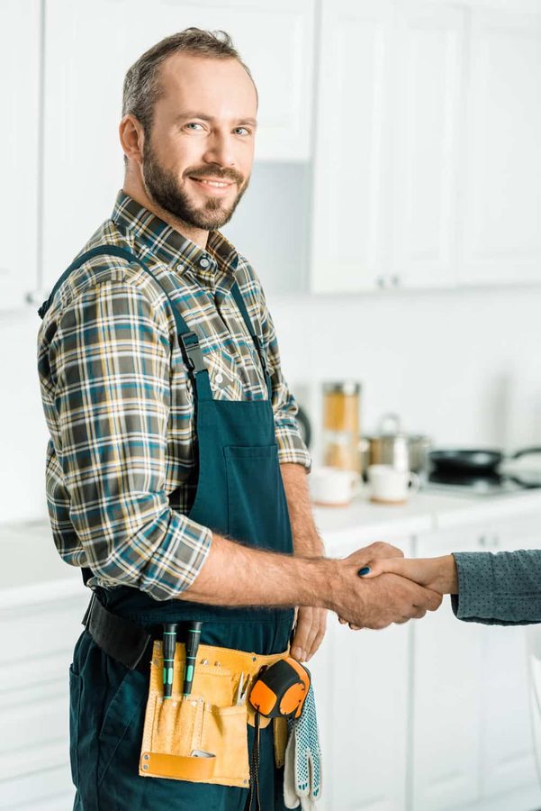 Smiling plumber holding tools