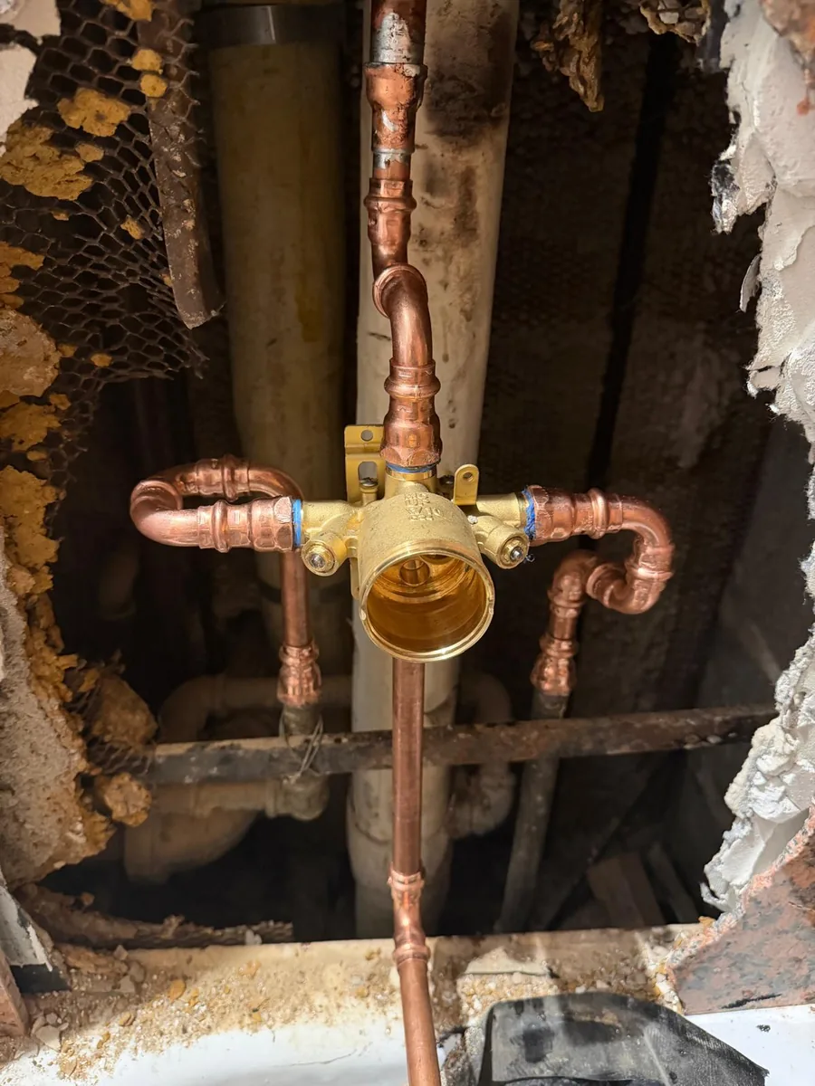 Shower valve and copper pipework visible through a wall opening