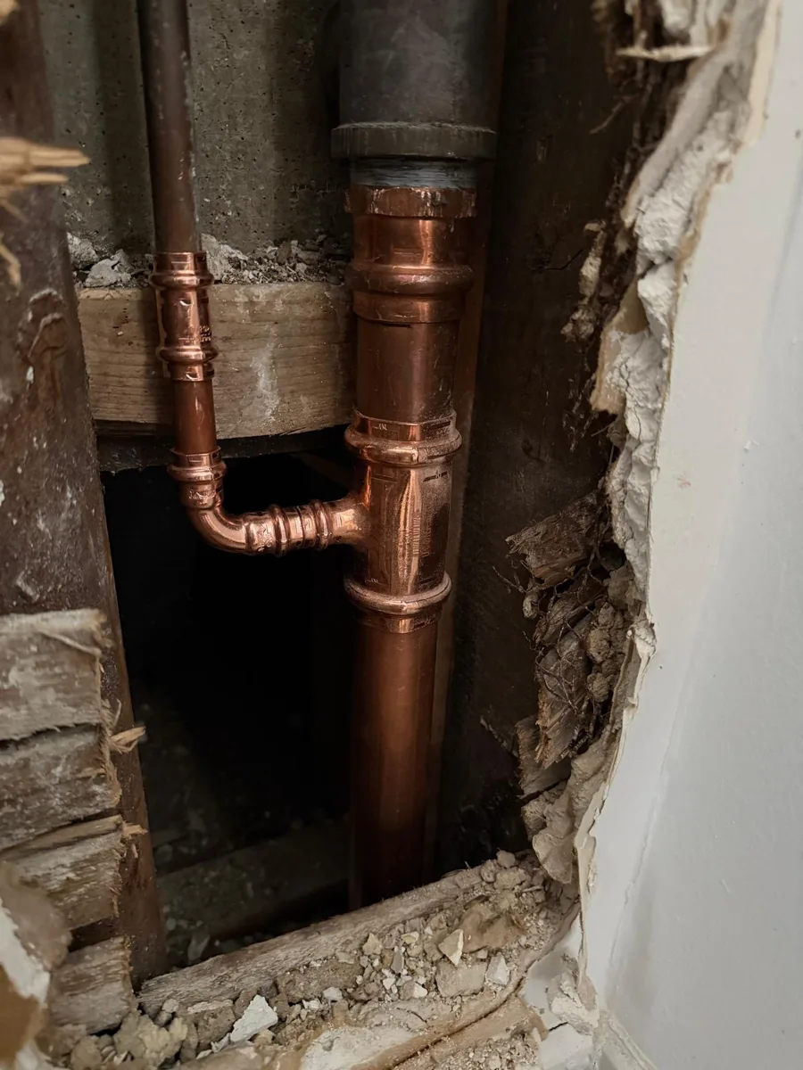 Copper and dark pipework visible inside a wall opening