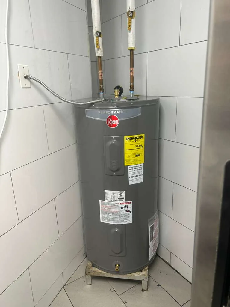 Tank water heater and exposed pipework against tiled walls