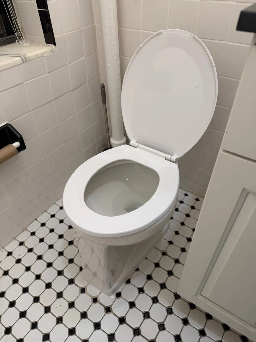 White toilet beside a tiled wall and patterned floor