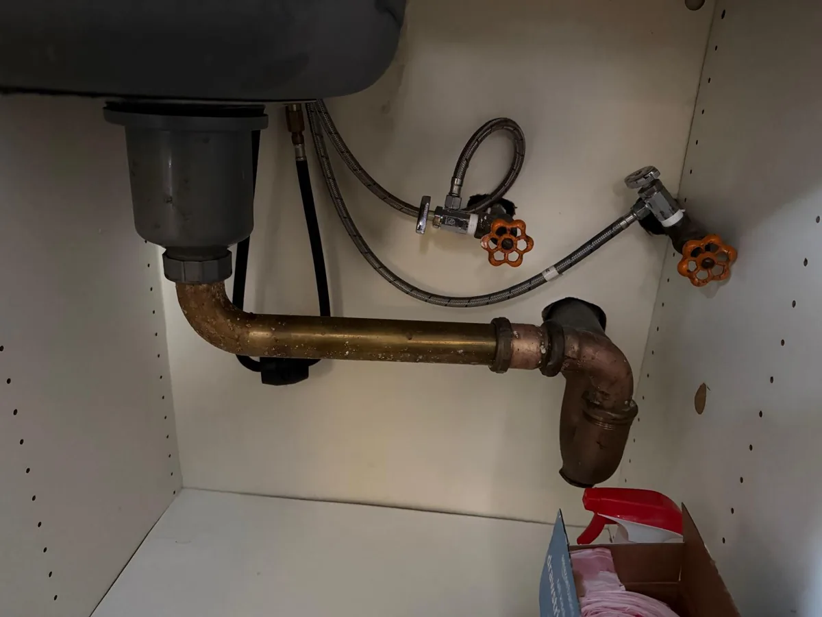 Drain pipe and water supply valves beneath a sink