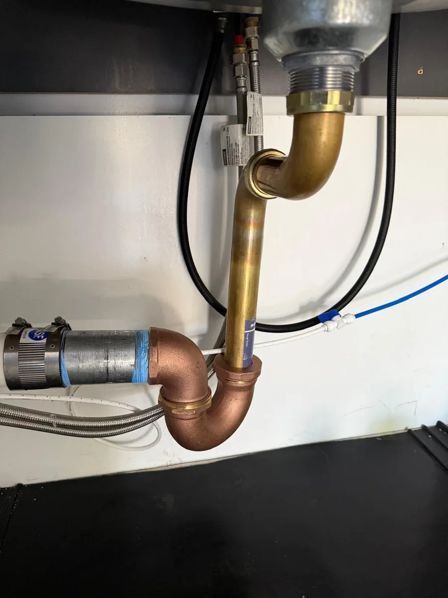 Metal drain pipework and supply connections beneath a sink